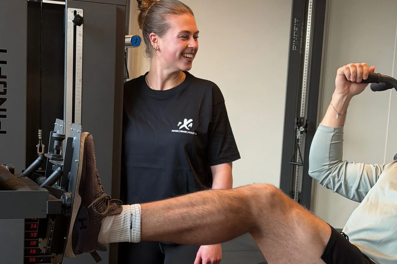 Eine Mitarbeiterin von PXA, einer Physiotherapiepraxis in Hamburg macht übungen mit einem Patienten Krankengymnastik am Gerät